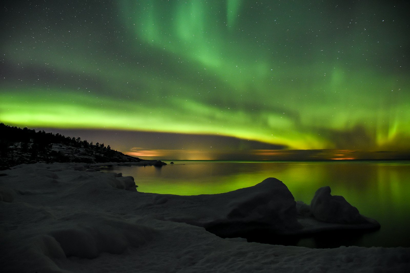 Green aurora borealis over a calm lake at night